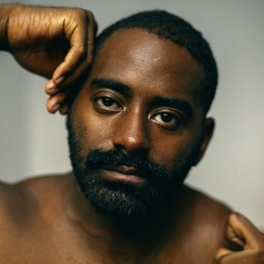 Nahaufnahme von Jerron, einem Schwarzen Mann, dessen Hände sein Gesicht umrahmen.