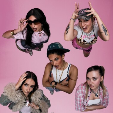 Sieben Personen stehen auf einem rosa Hintergrund und werden aus der Vogelperspektive fotografiert. Sie blicken ausdrucksstark nach oben in die Kamera und zeigen unterschiedliche, teils verspielte Gesten. Die Kleidung ist bunt und individuell gestylt.