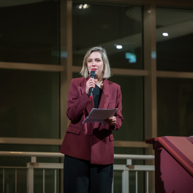 Festivaleröffnung im Foyer des Schauspiel Hannover. Das Foto zeigt Melanie Zimmermann. Sie steht auf einer Treppe und spricht in ein Mikrofon.