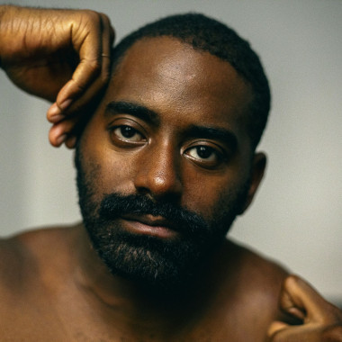 Close up of Jerron, a dark skinned black man with both hands framing the face