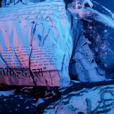 Close-up of several beanbags lying on top of each other. They are printed all over with black and white drawings, words and pictures.