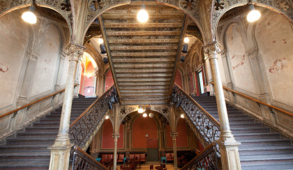 The photo shows the staircase of the Cumberland Gallery. It is a very high, open space with cast-iron supports and banisters.
