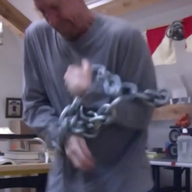 Ein Videostill der Arbeit TRI TEMPI (2023) von William Forsythe. Es ist ein Tryptichon und zeigt Forsythe stehend mit einem Objekt in der Hand.